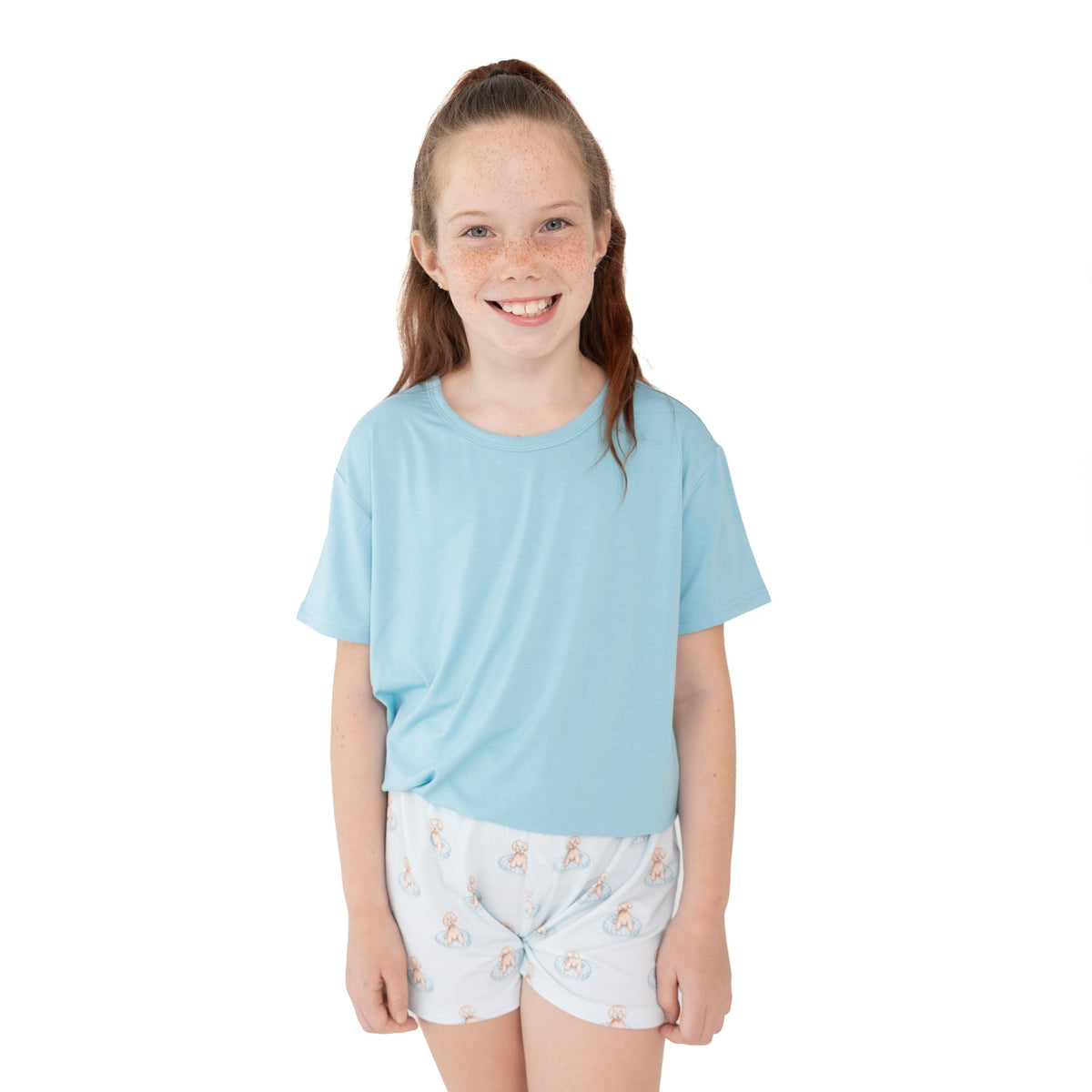 Youth girls shorts set with a solid short-sleeve top and shorts printed with puppies splashing in little blue pools.