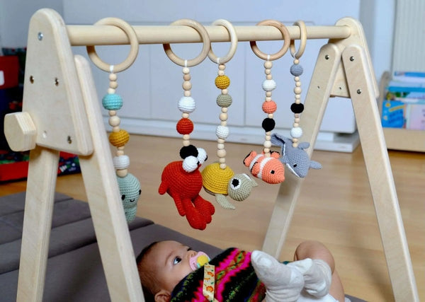 Wooden baby play gym with birch frame and five colorful crochet hanging toys