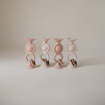 Mushie HexaPop Suction Toy in vibrant colors, made from food-grade silicone, shown attached to a smooth surface.