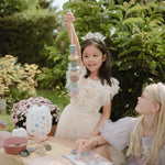 Mushie silicone lacing beads toy set with colorful shapes and string, displayed on a natural wood surface.