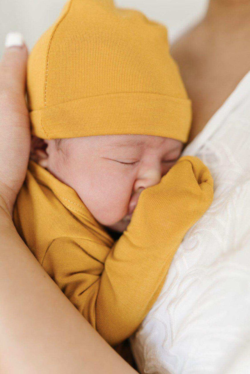 Knot hat in mustard color on newborn, made from bamboo viscose and spandex, cozy and stylish.