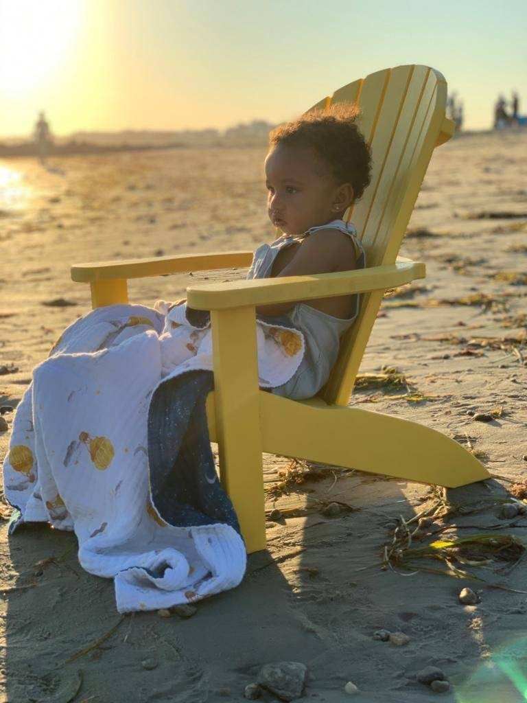 Child wrapped in a Mystical Night Blanket on a beach at sunset.