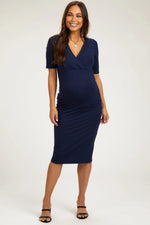 Navy blue maternity midi dress with a wrap v-neckline and short sleeves, worn with heeled sandals.