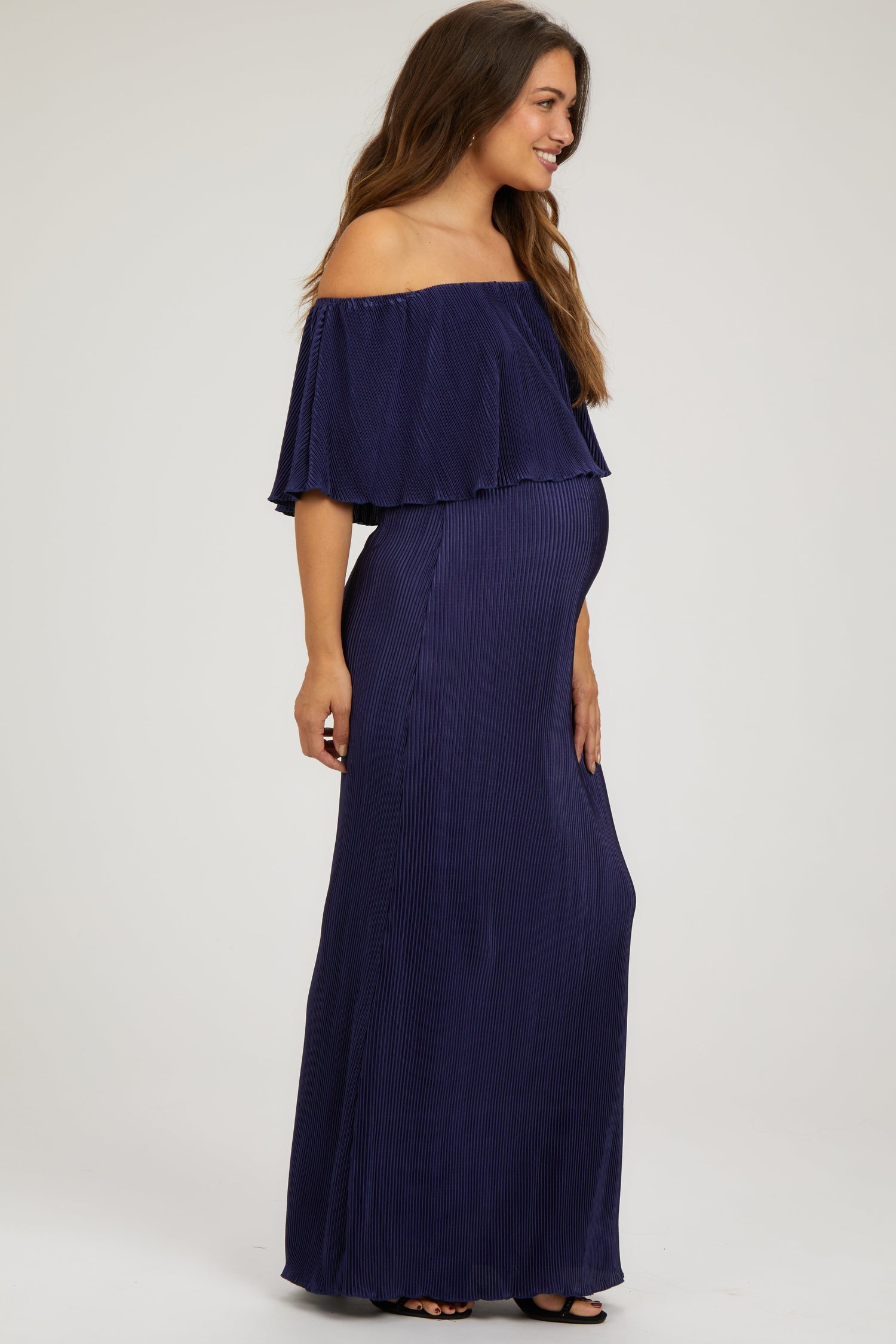 Model wearing a navy pleated ruffle off-shoulder maternity maxi dress by PinkBlush, smiling.