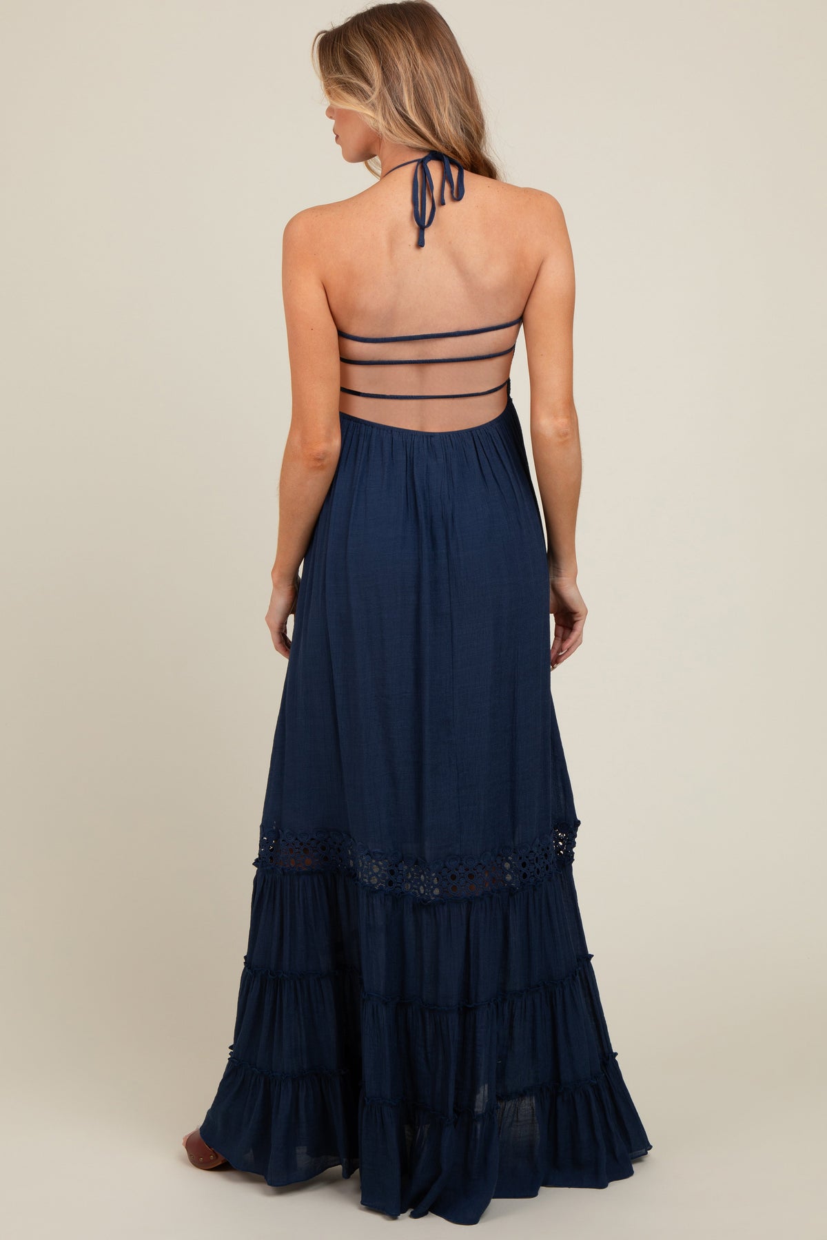 Model wearing a navy smocked open back maternity maxi dress, standing gracefully.