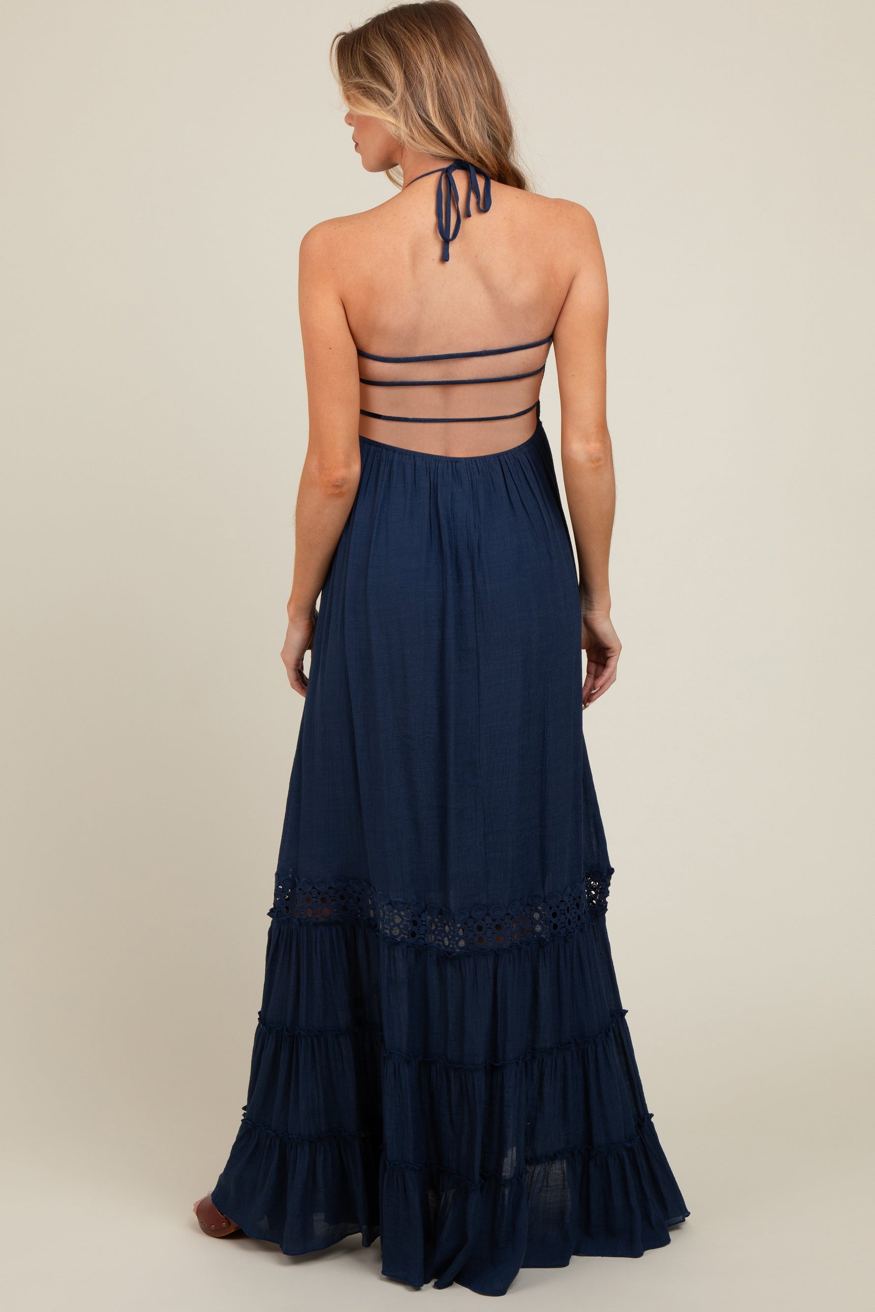 Model wearing a navy smocked open back maternity maxi dress, standing gracefully.