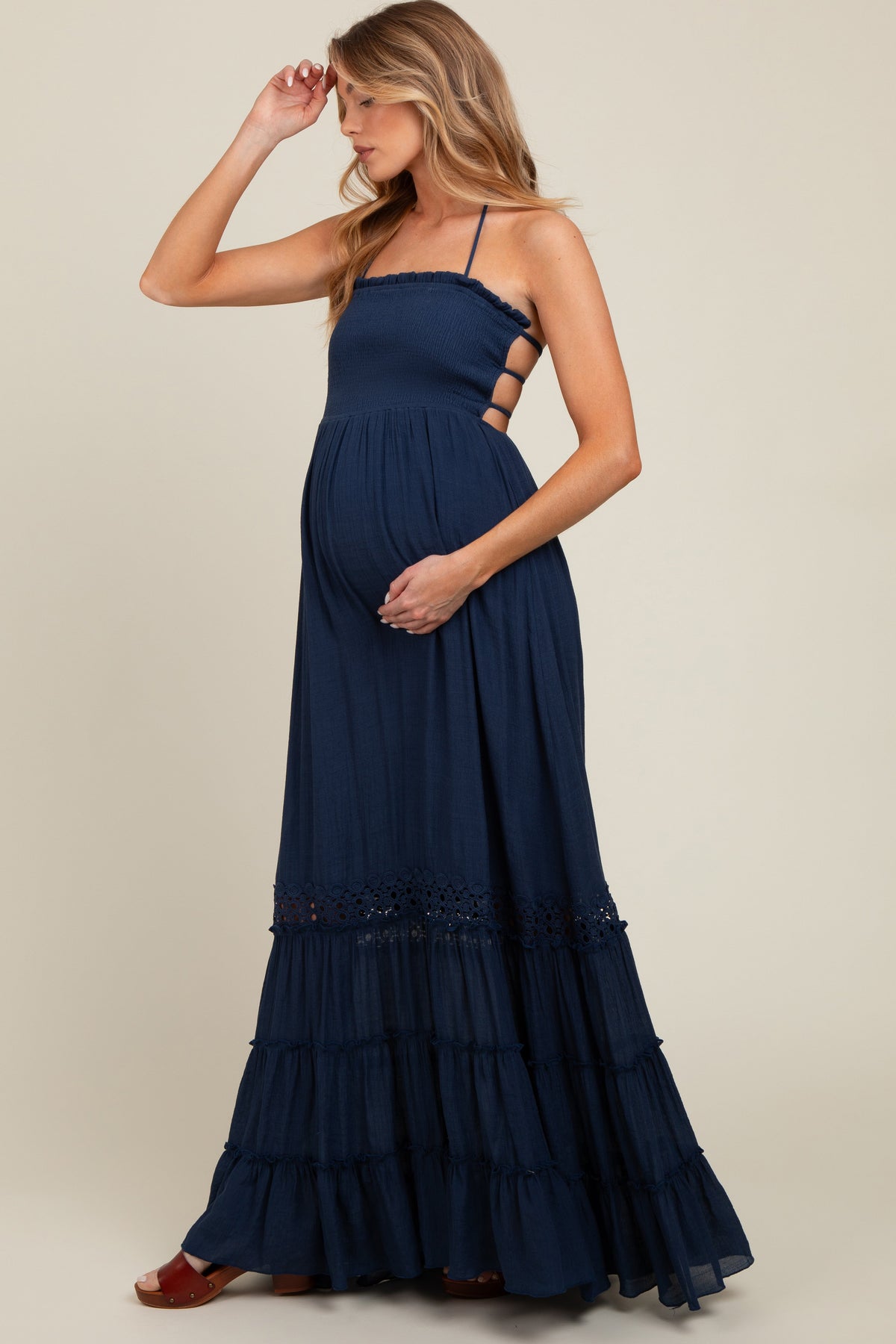Model wearing a navy smocked open back maternity maxi dress, standing gracefully.