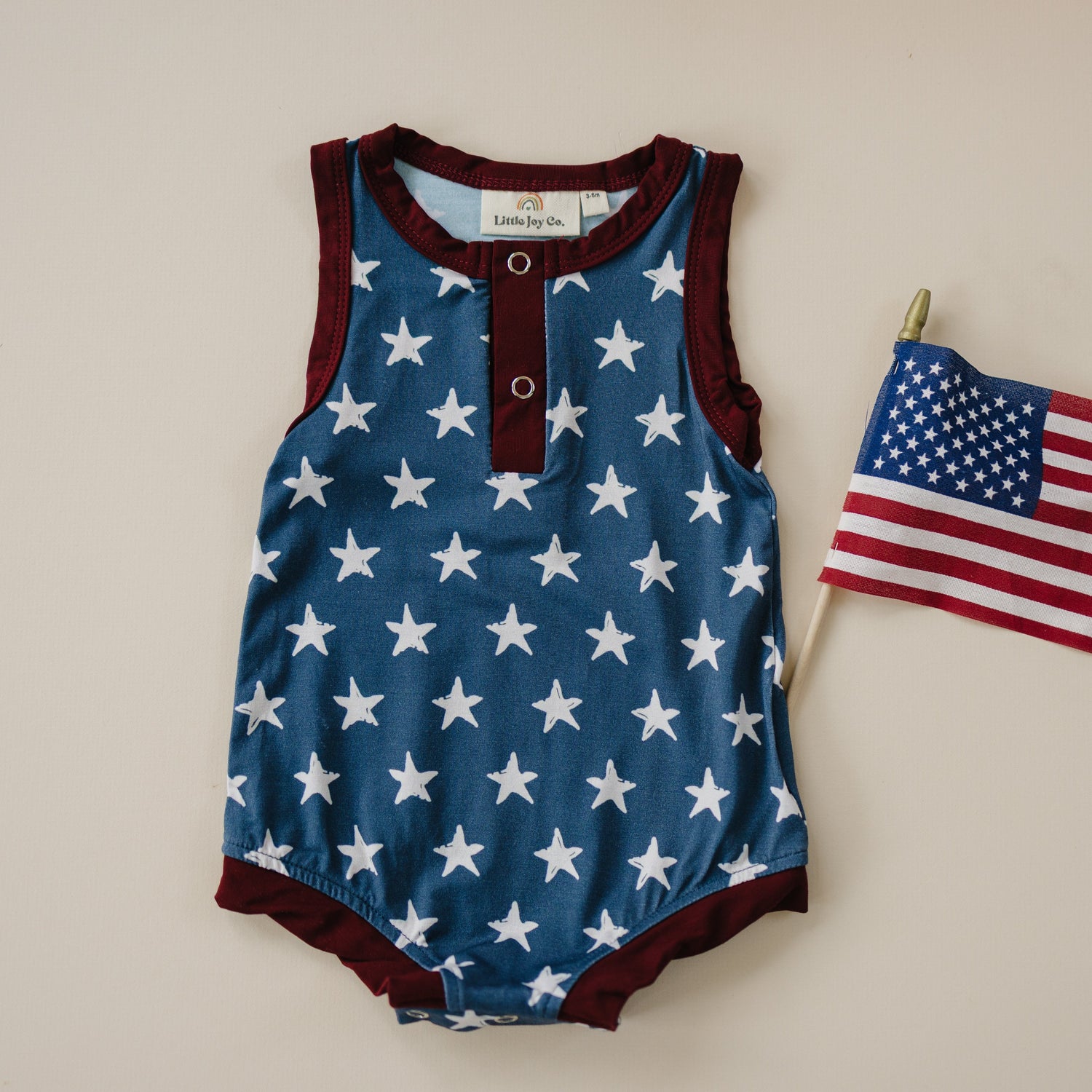 Little Joy Co. baby wearing a navy blue bamboo romper with white star print and Henley buttons