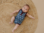 Little Joy Co. baby wearing a navy blue bamboo romper with white star print and Henley buttons