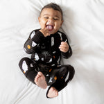 Baby bamboo footed romper in black with ghost, pumpkin, bat and cobweb print and fold-over cuffs.