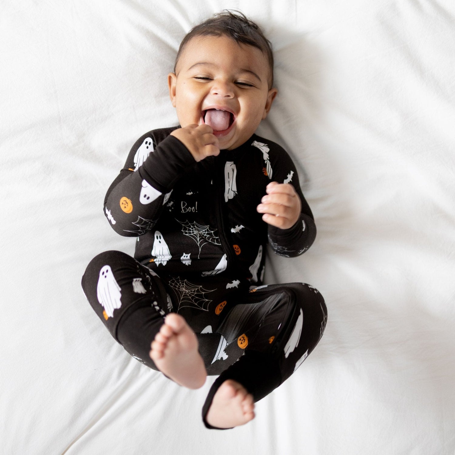 Baby bamboo footed romper in black with ghost, pumpkin, bat and cobweb print and fold-over cuffs.