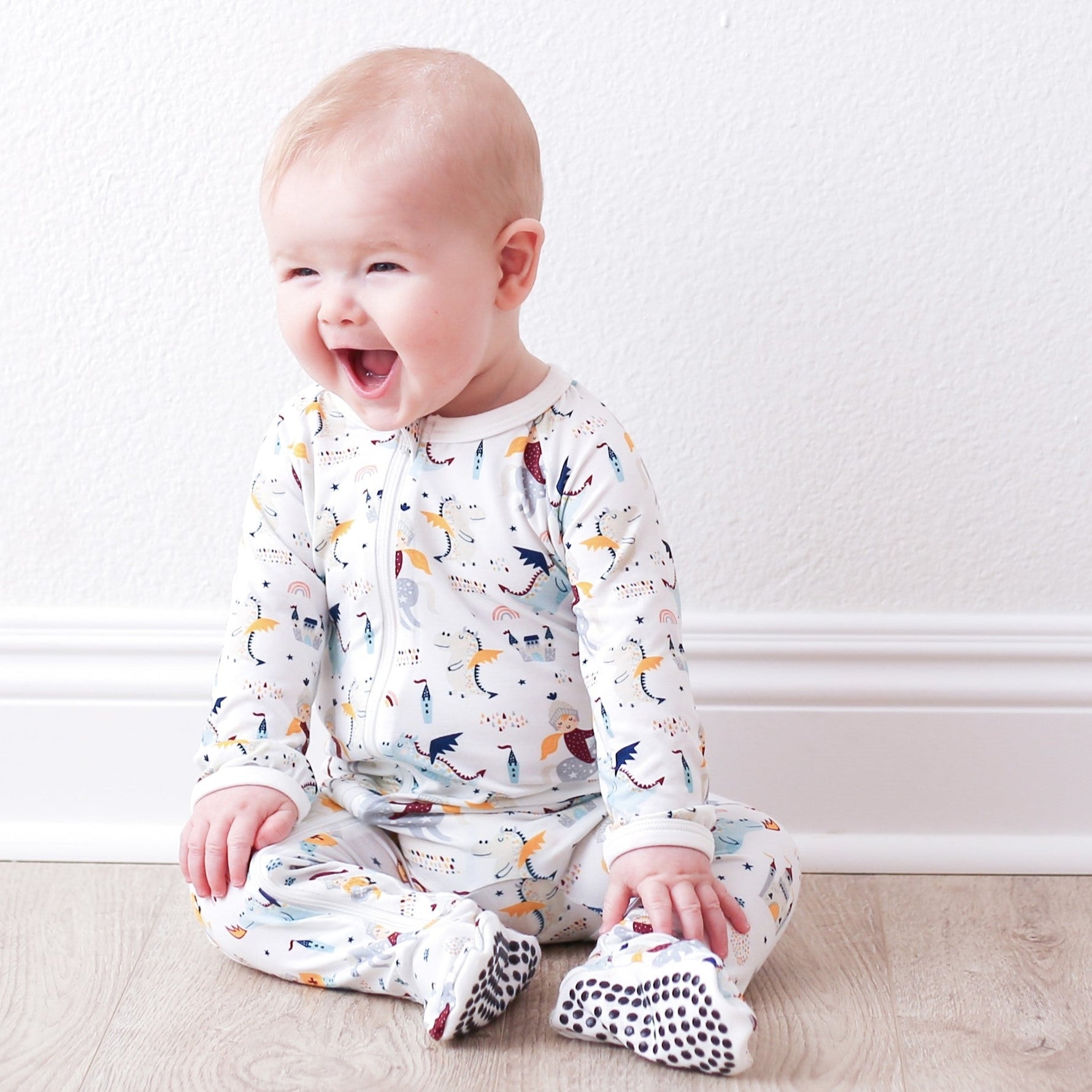 Baby footie pajamas in a knight-themed print with covered feet and a front zipper