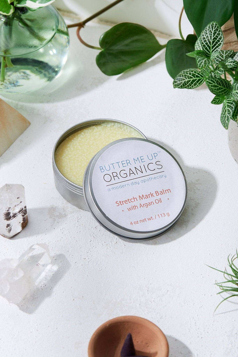 Organic Body Butter with Argan Oil in open tin, surrounded by plants and crystals.