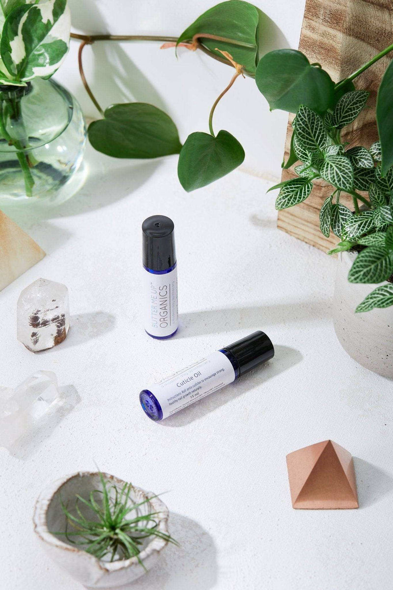 Organic cuticle oil bottles on a white surface with plants in the background.