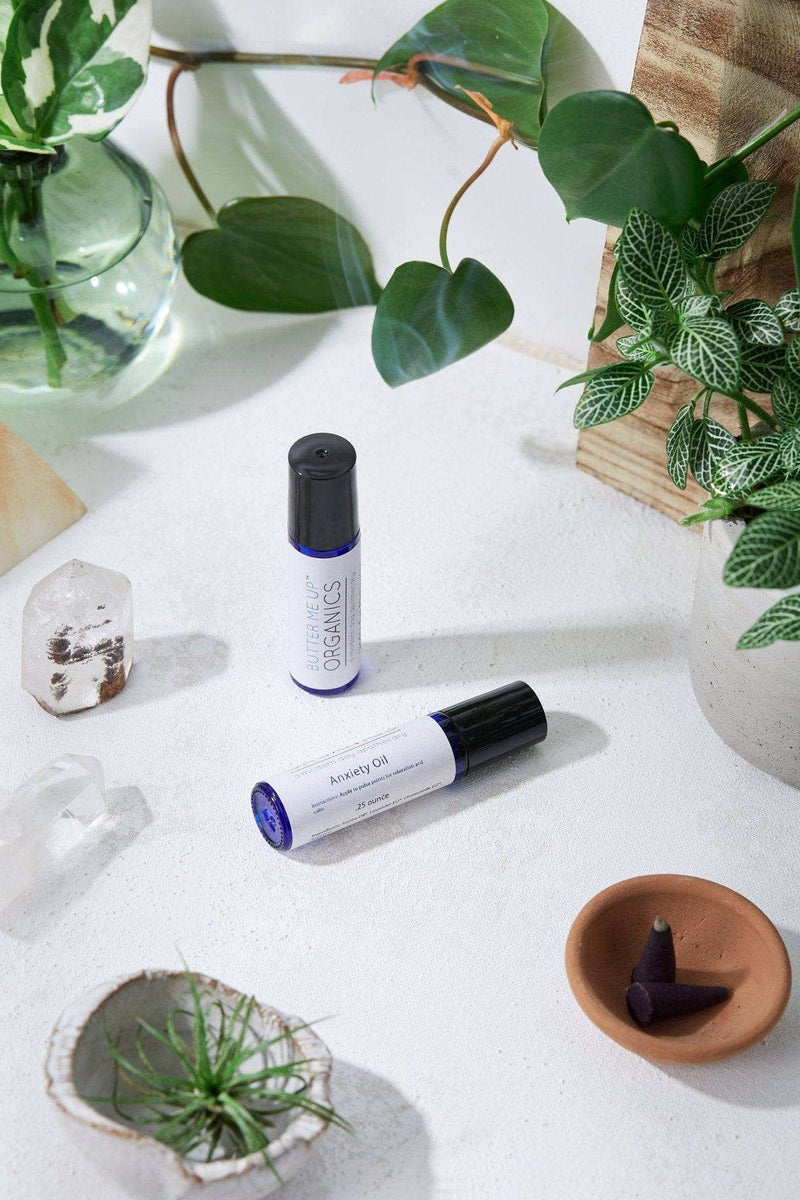 Organic essential oils roll-on with basil, glass vial, and stainless steel roller in a natural setting.