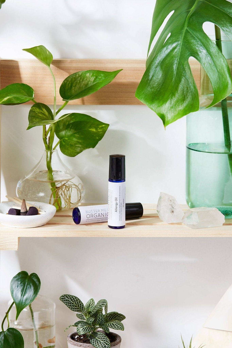 Organic histamine blocker oil roll-on for allergy relief displayed on a shelf with plants and crystals.