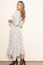 Baby girl wearing an organic Ivory Floral Smocked Handkerchief Hem Maxi Dress, playing happily.