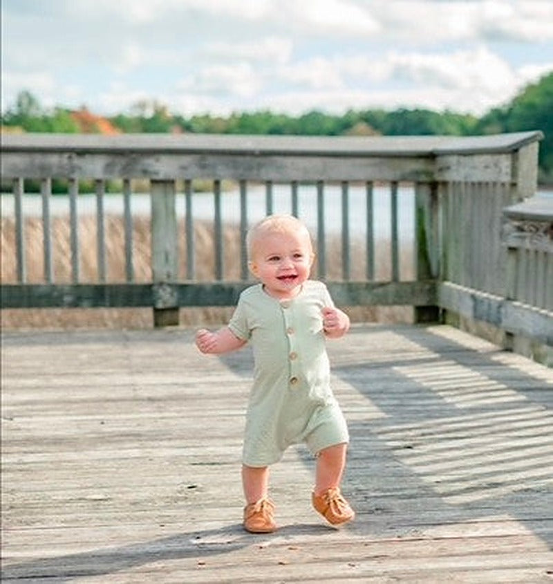 Short sleeve baby romper with front buttons and a relaxed fit, shown as a one-piece garment.