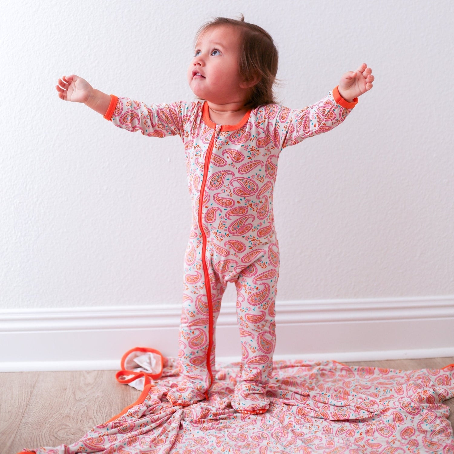 Baby footie pajamas in a paisley and floral print with footed legs and a full-length zipper.
