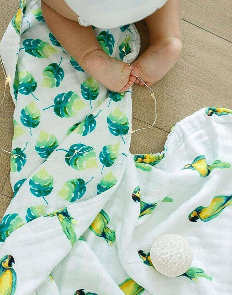 Parrots Organic Blanket with watercolor print and baby playing.