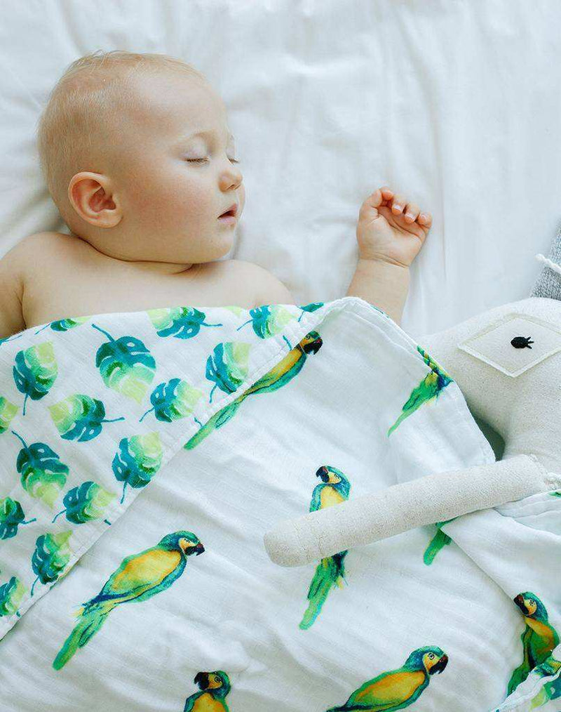 Baby sleeping with Parrots Organic Snug Blanket, featuring watercolor parrot print, made from GOTS certified cotton.