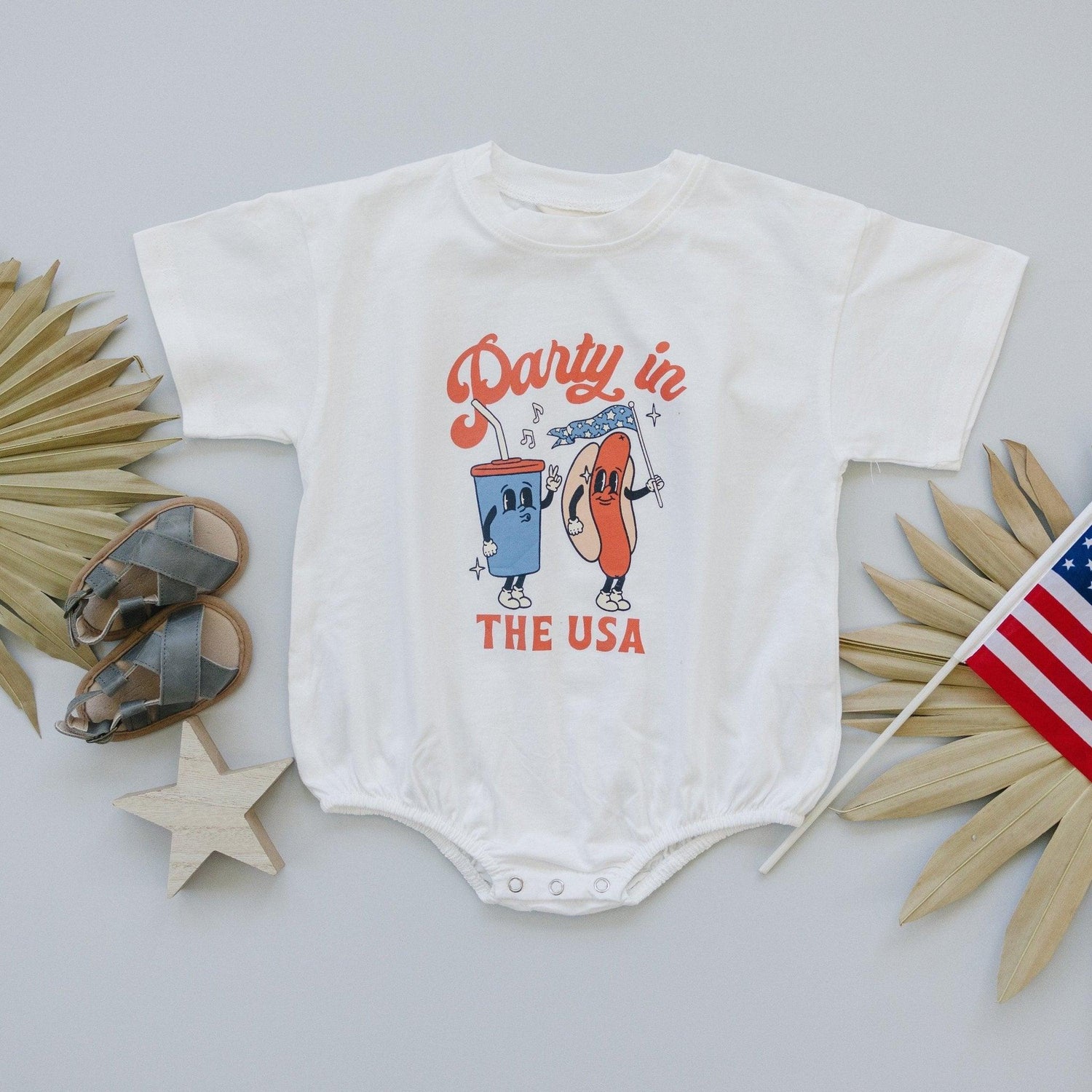 Little Joy Co. organic baby t-shirt romper with 'Party in the USA' graphic, front view