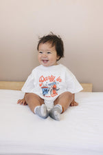 Little Joy Co. organic baby t-shirt romper with 'Party in the USA' graphic, front view