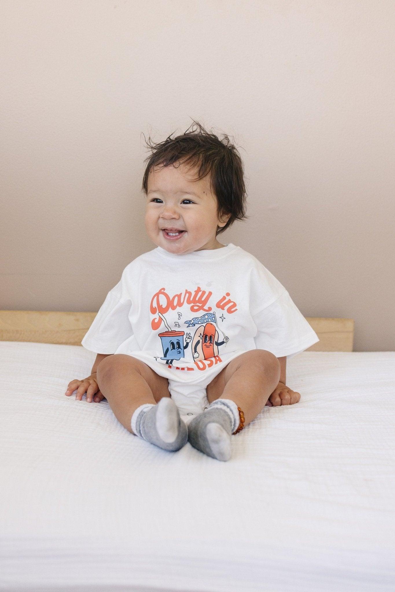 Little Joy Co. organic baby t-shirt romper with 'Party in the USA' graphic, front view