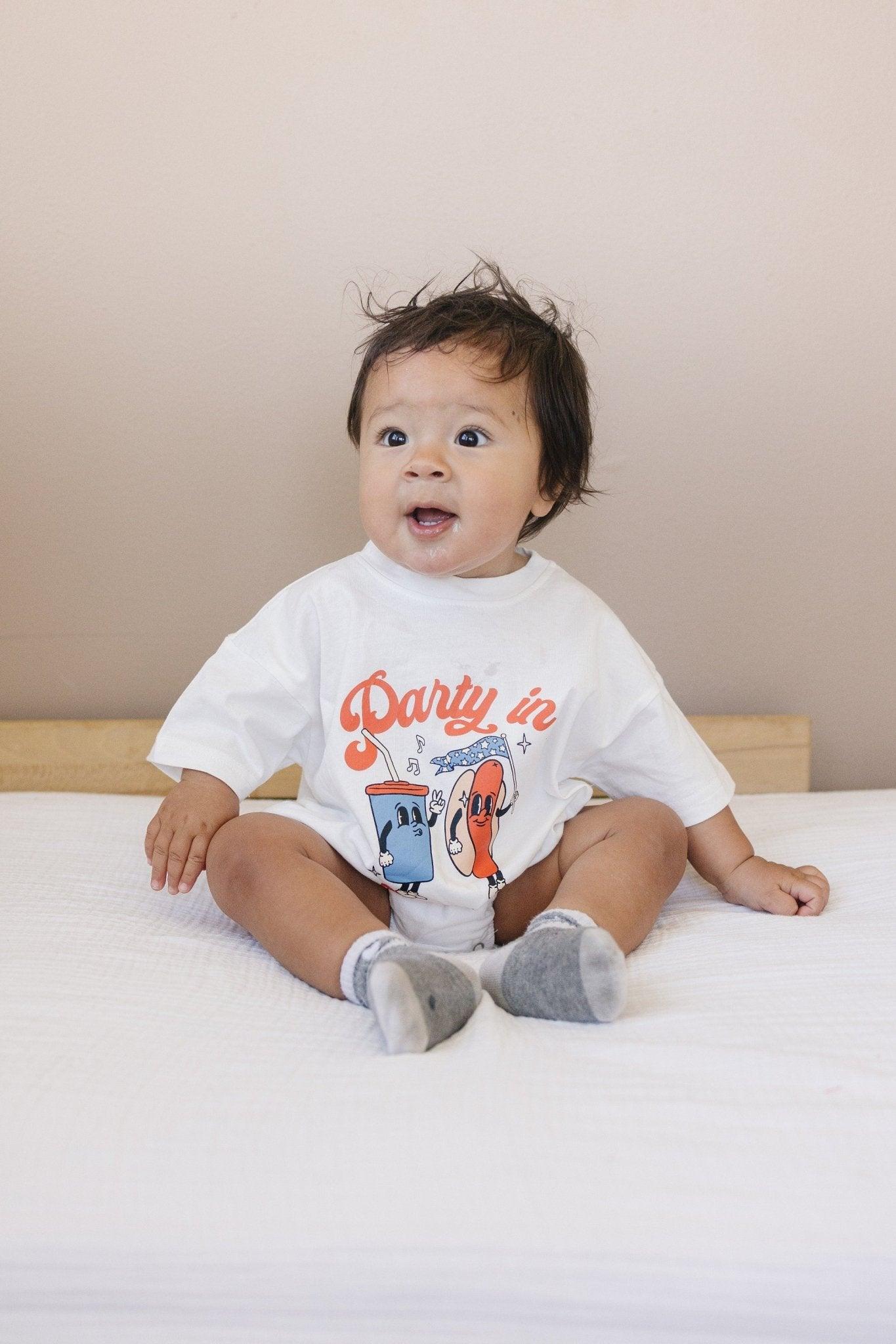 Little Joy Co. organic baby t-shirt romper with 'Party in the USA' graphic, front view