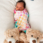Pastel checked baby swaddle blanket in soft muted colors, folded to show the check pattern