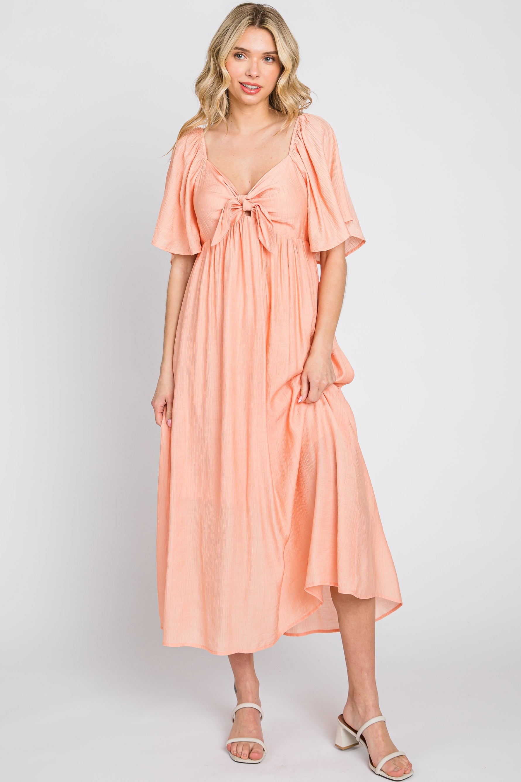 Model wearing a peach front tie ruffle sleeve midi dress by PinkBlush, styled for a casual outing.