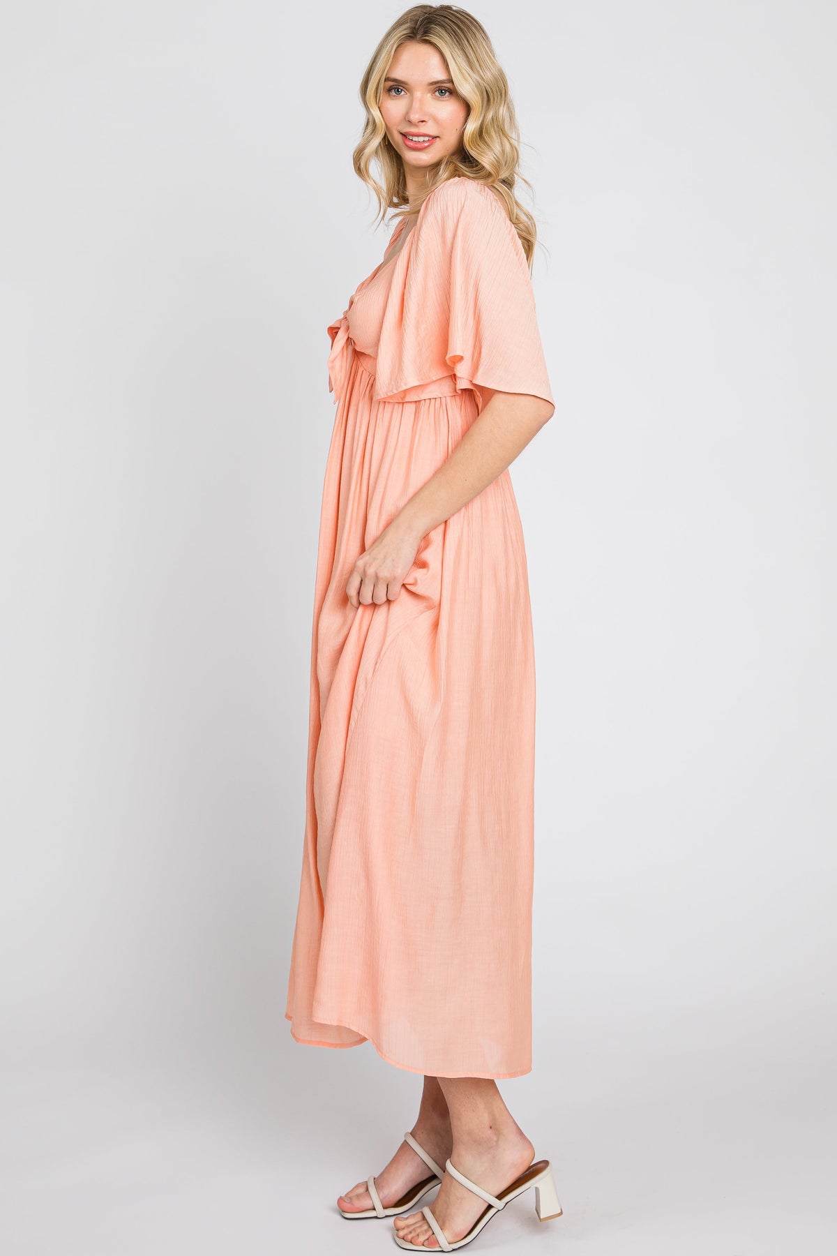 Model wearing a peach front tie ruffle sleeve midi dress by PinkBlush, styled for a casual outing.