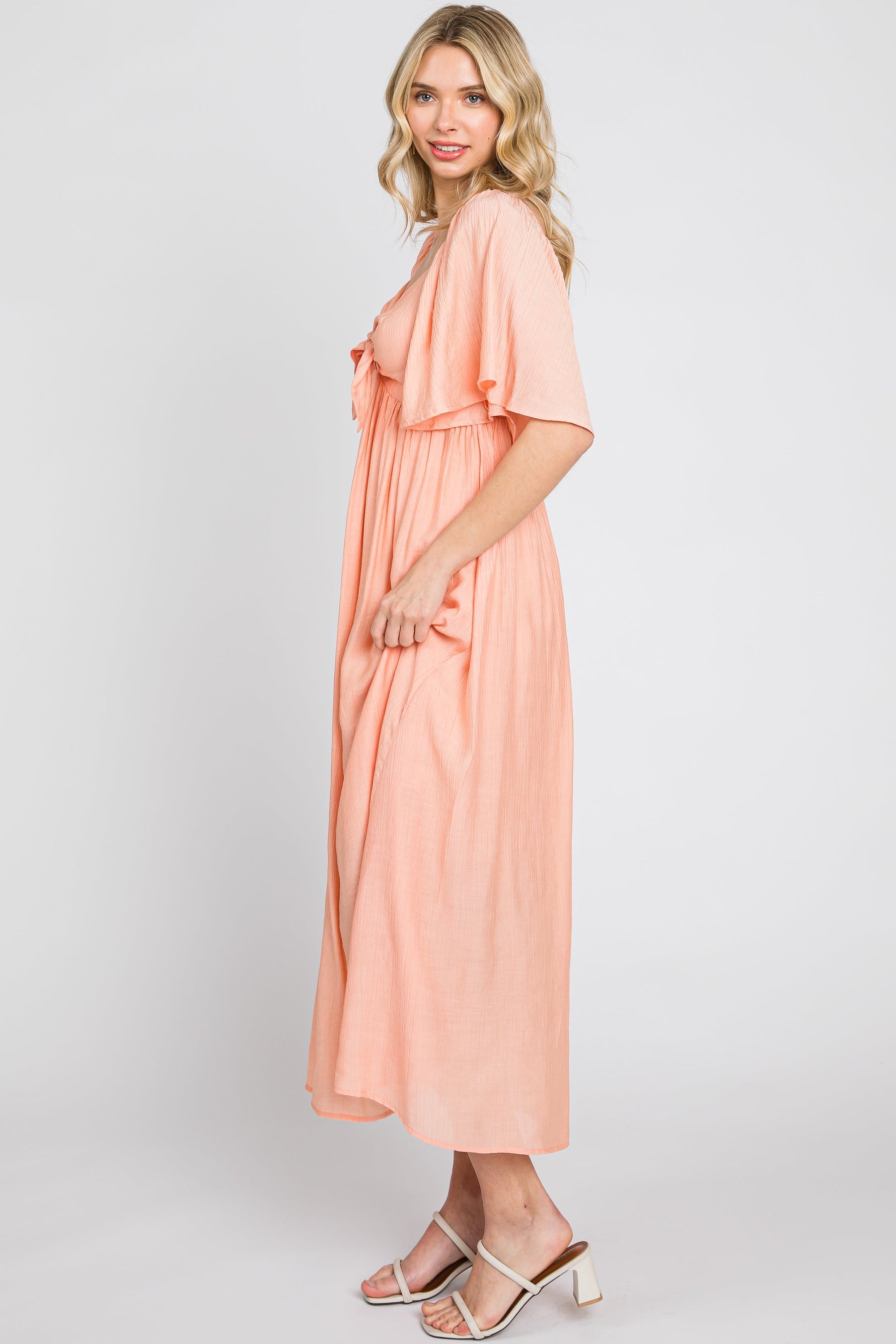 Model wearing a peach front tie ruffle sleeve midi dress by PinkBlush, styled for a casual outing.