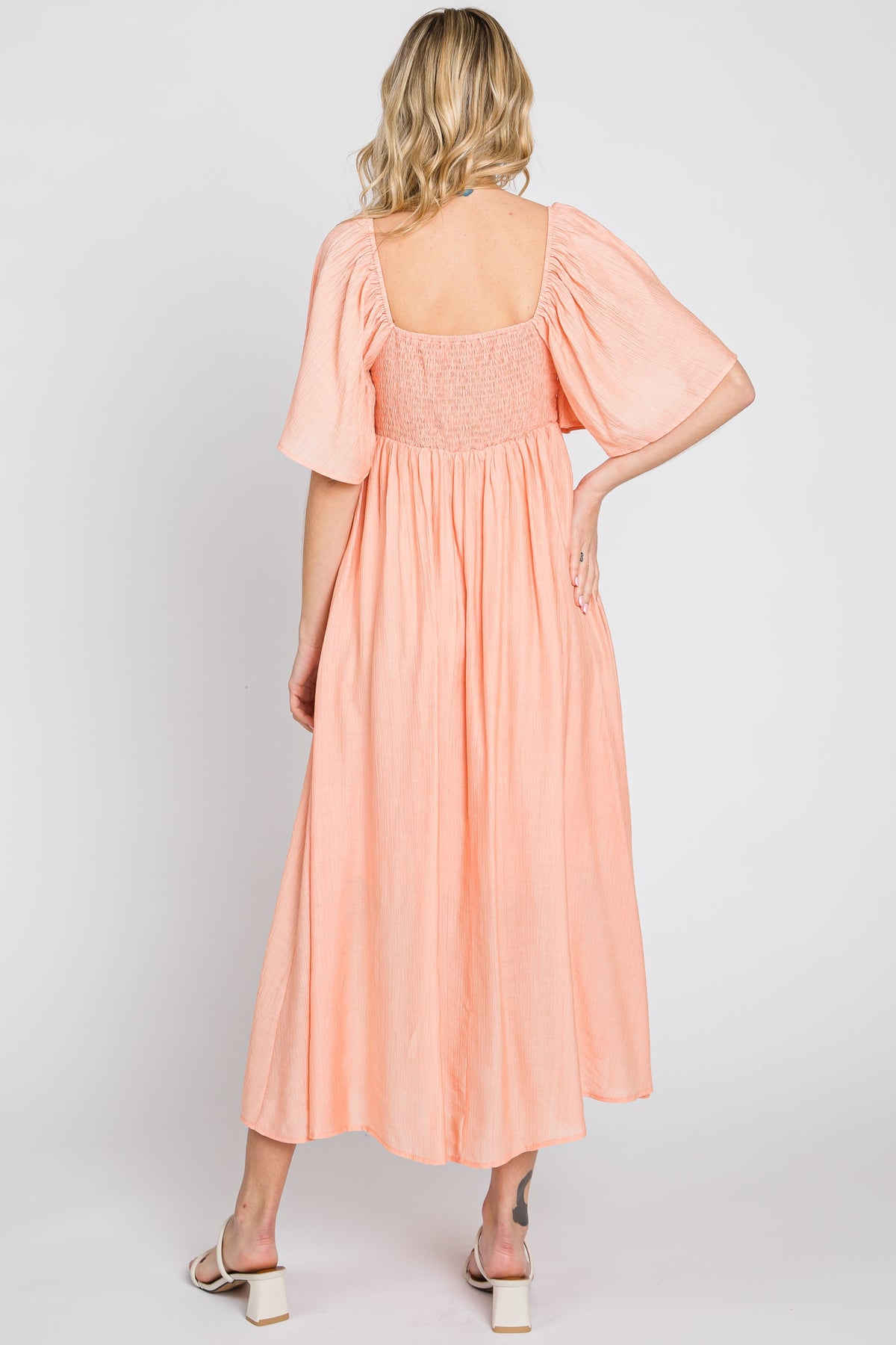 Model wearing a peach front tie ruffle sleeve midi dress by PinkBlush, styled for a casual outing.
