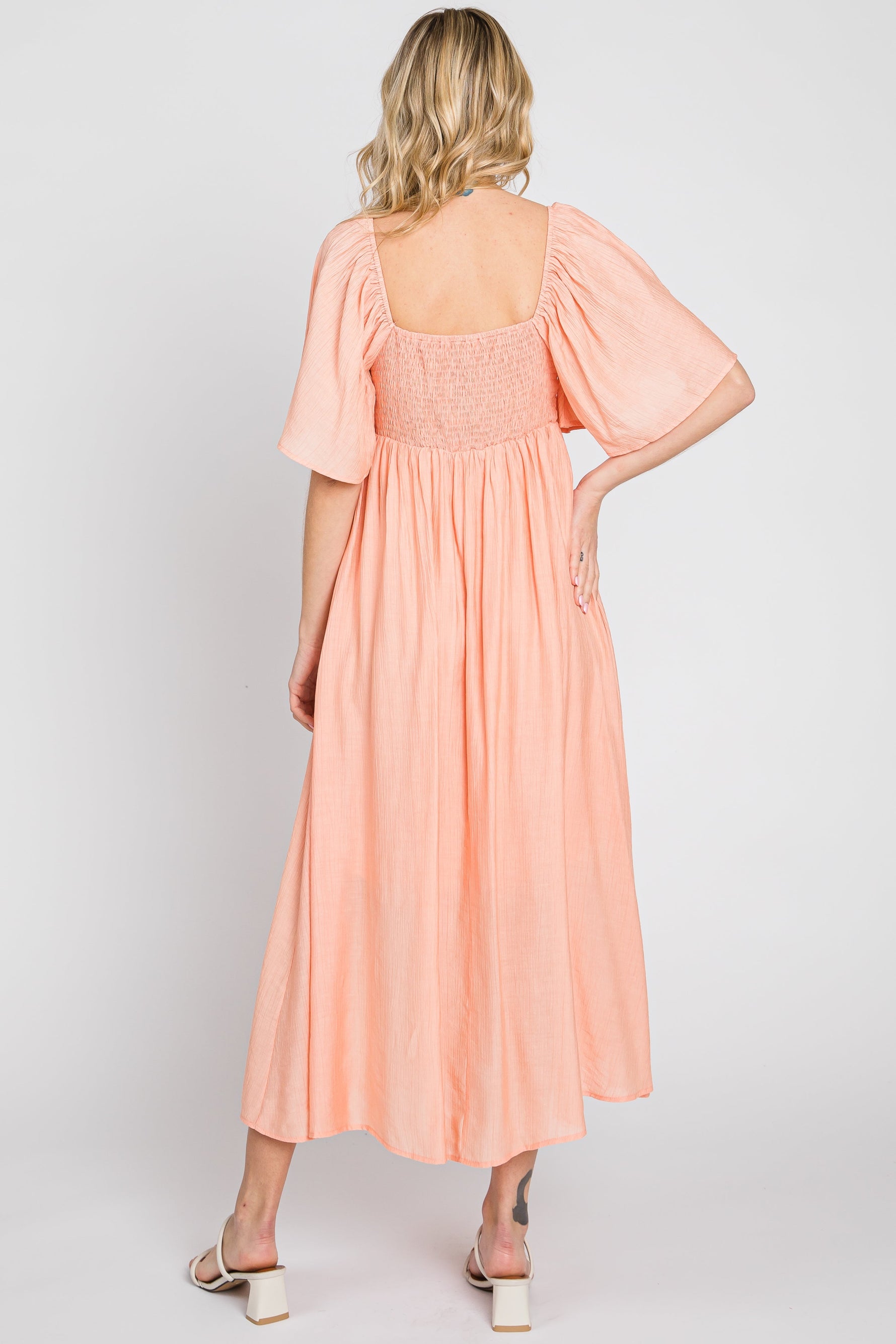 Model wearing a peach front tie ruffle sleeve midi dress by PinkBlush, styled for a casual outing.