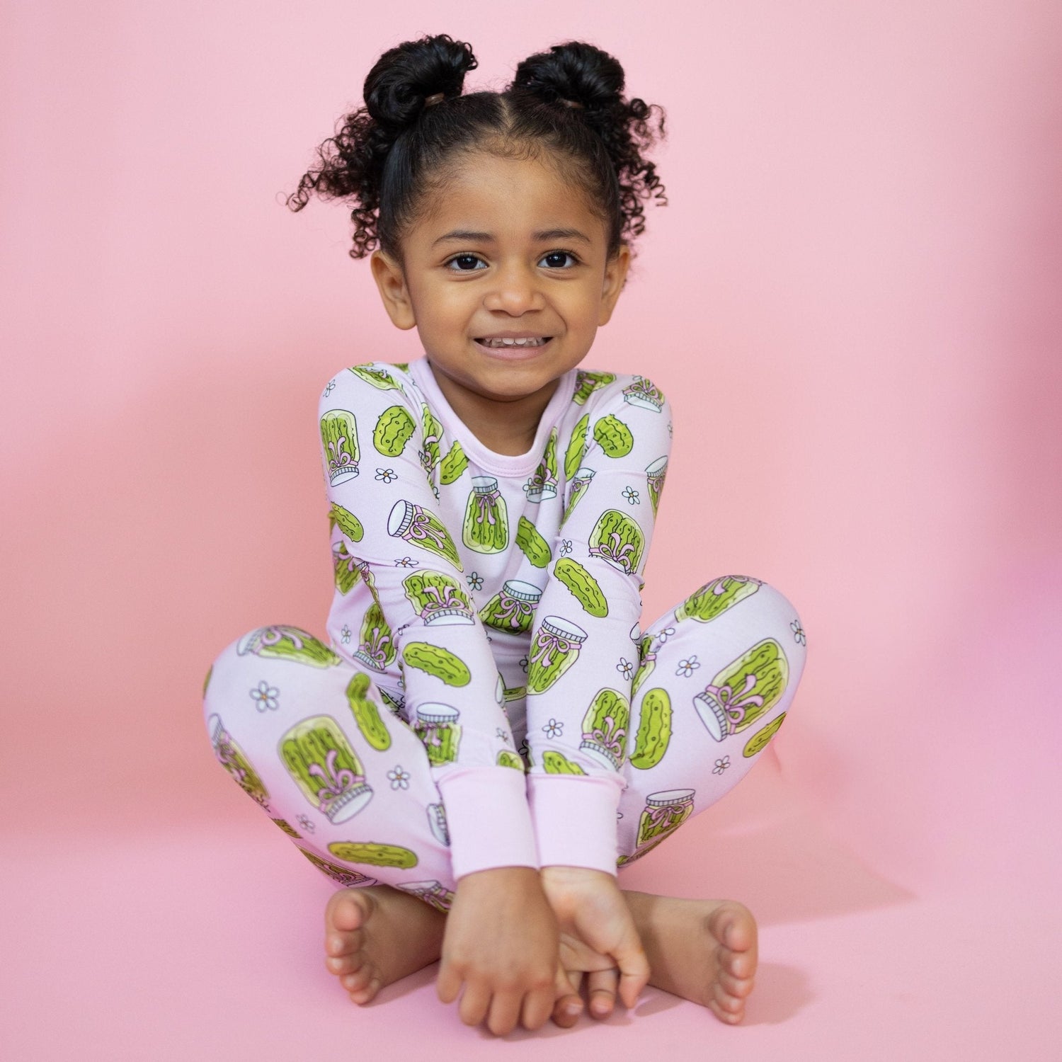Toddler long-sleeve pajama set in pink with a pickles and bows print, matching long pants.