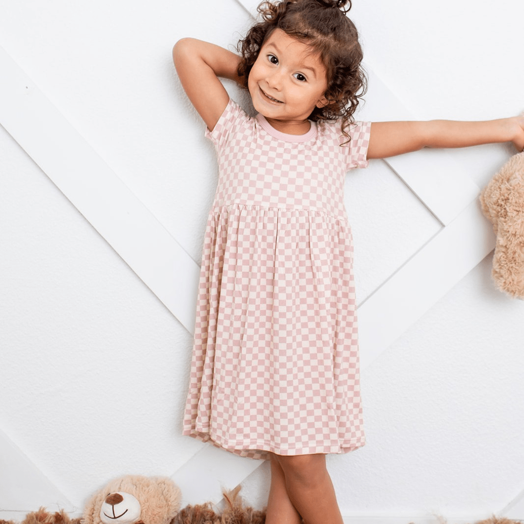 Pink checked short-sleeve dress on a toddler, with a full twirl-ready skirt.