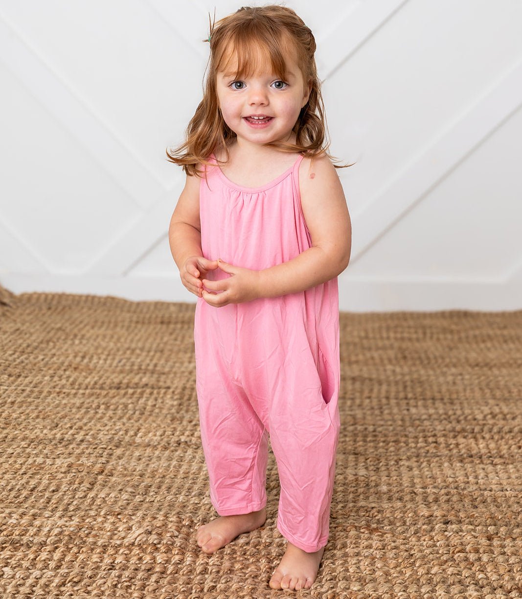 Pink one-piece jumpsuit with pockets worn by a toddler