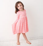Long sleeve baby dress in pink with a petal print, twirl-ready skirt