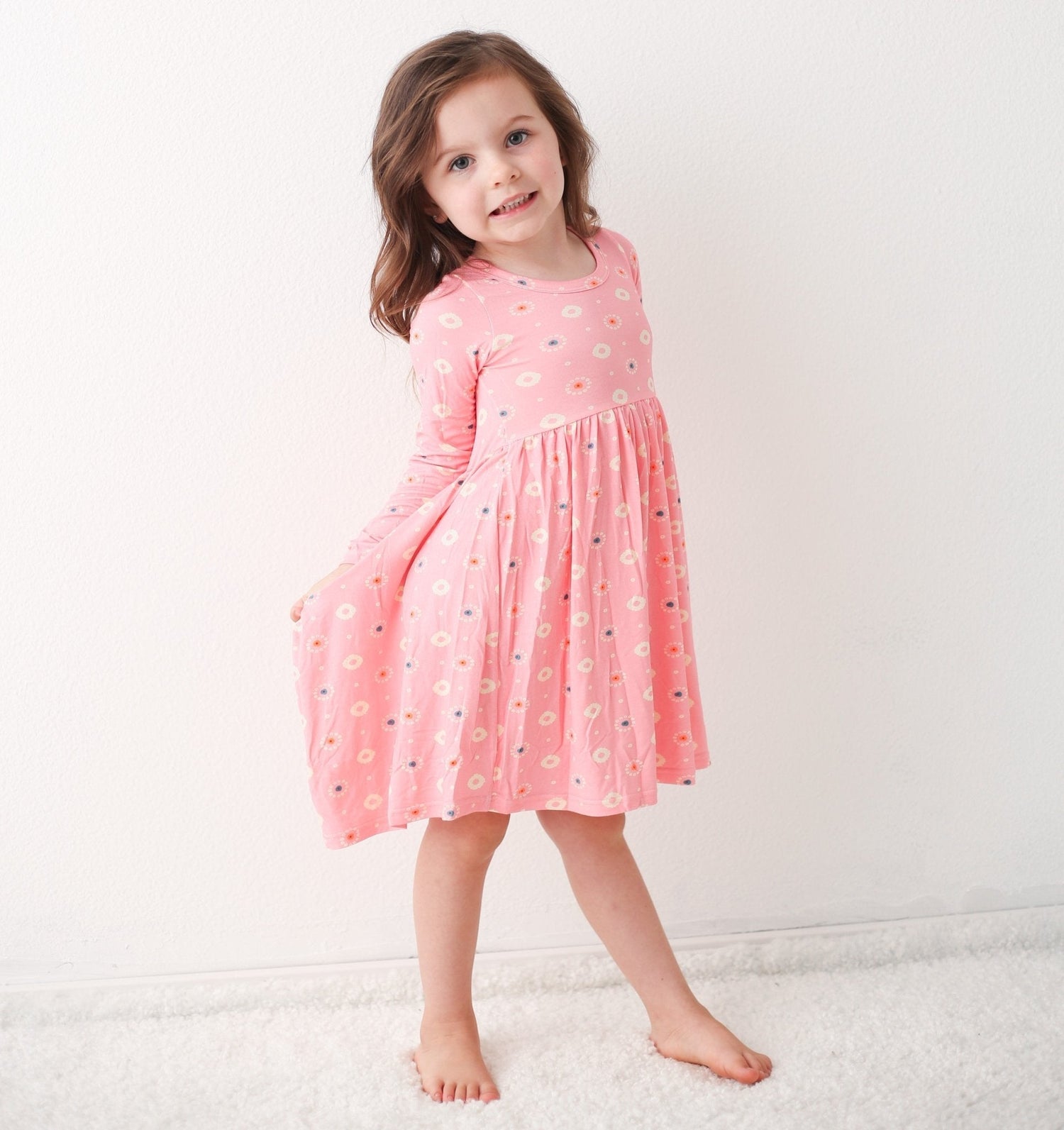 Long sleeve baby dress in pink with a petal print, twirl-ready skirt