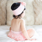 Baby wearing a rose-pink ruffle bloomer with back ruffles and a matching stretchy headband.