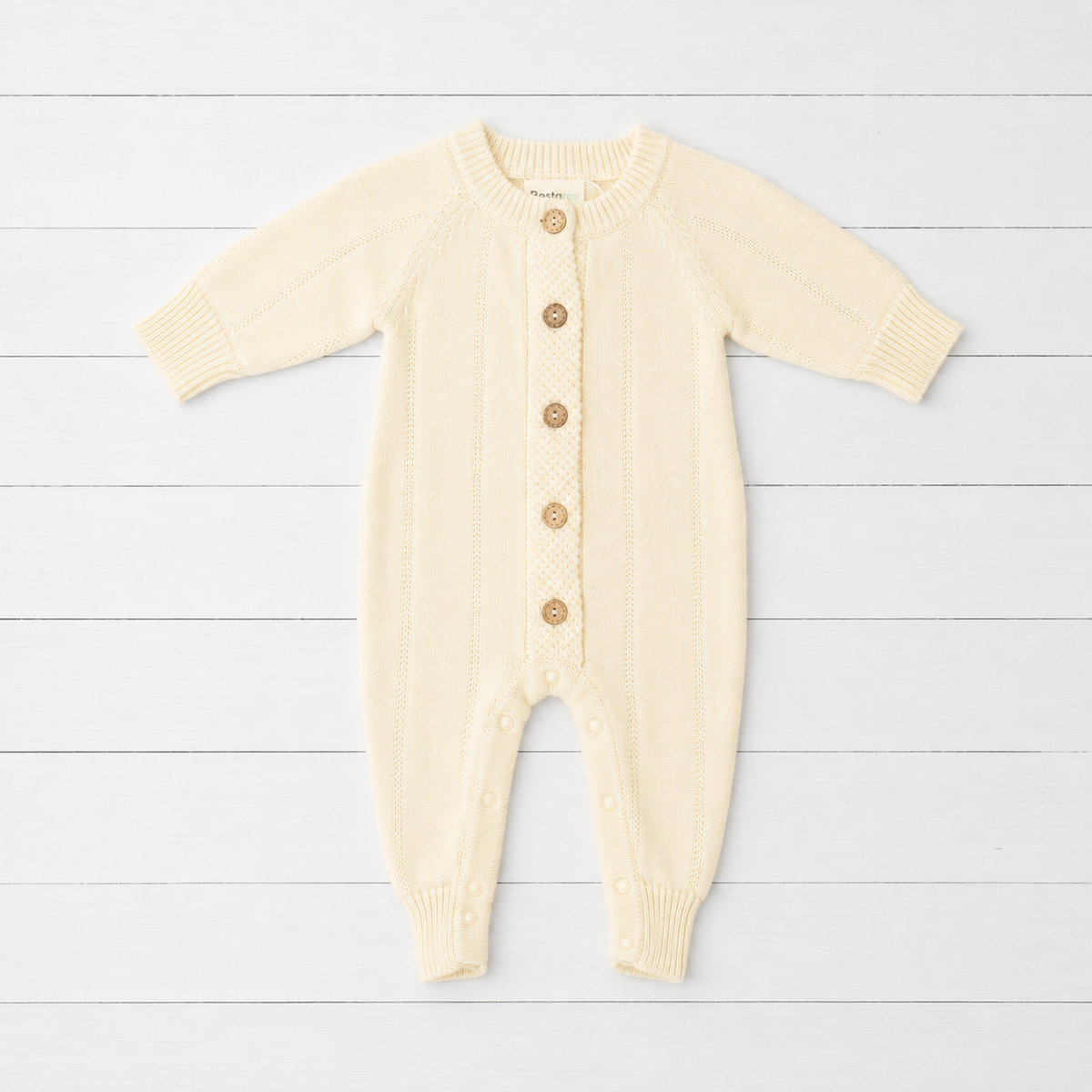 Buttercream pointelle knit baby footie romper with front button placket and long sleeves with ribbed cuffs