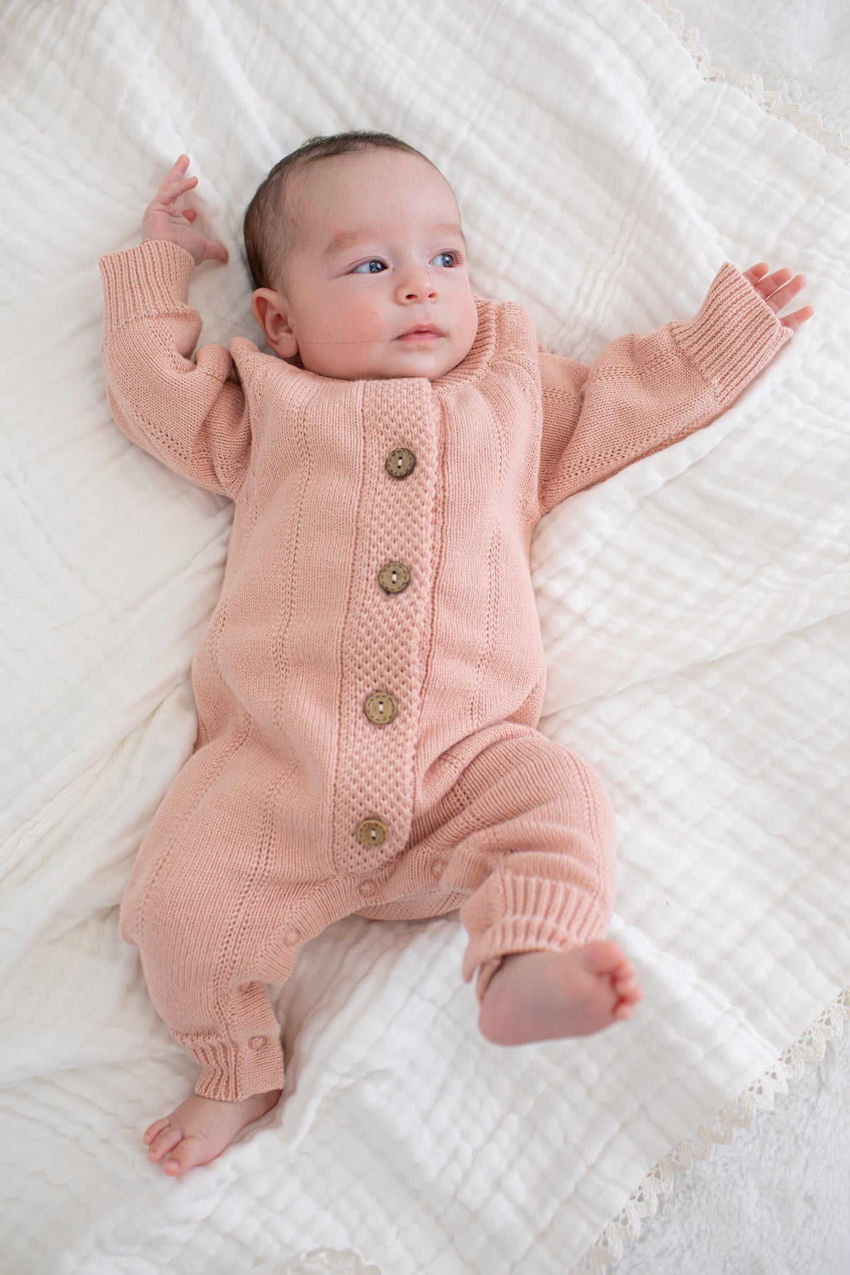 Tea rose pointelle knit baby romper with long sleeves, ribbed cuffs and buttons down the front