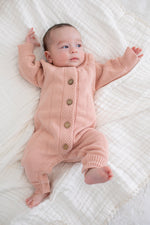 Tea rose pointelle knit baby romper with long sleeves, ribbed cuffs and buttons down the front