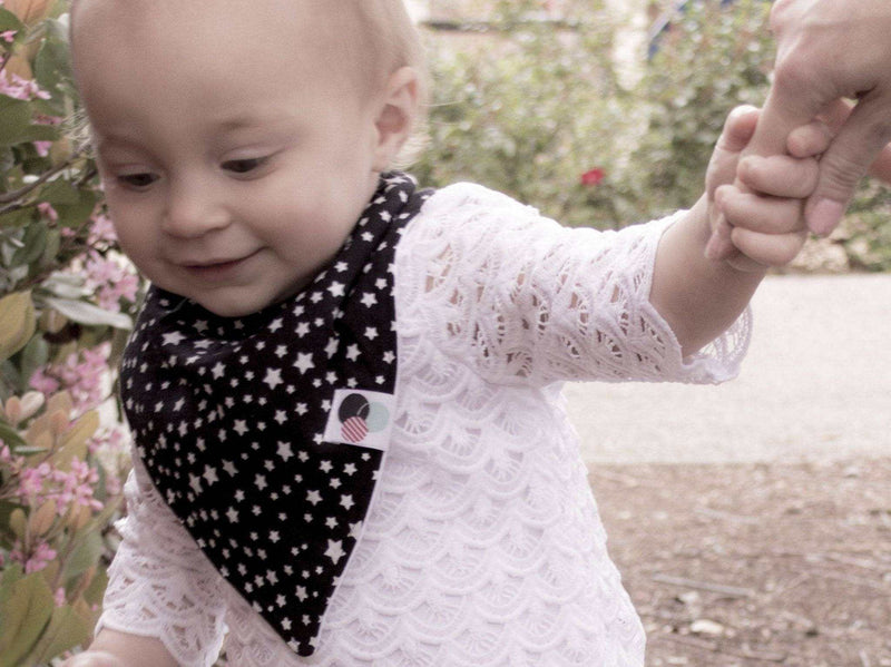 Baby wearing a Premium Plus Baby Bib, black and white star design, soft organic cotton, adjustable snaps.