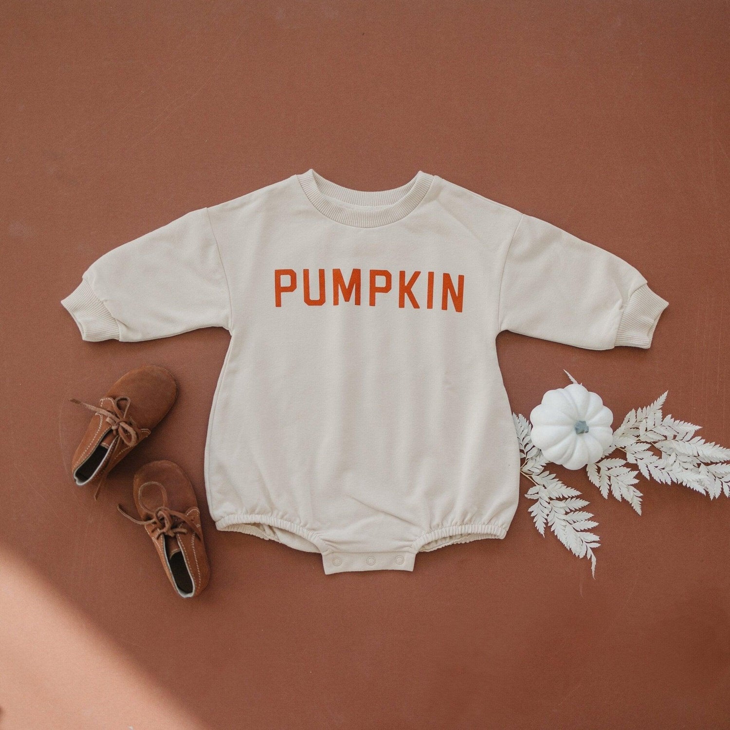 Oversized sweatshirt romper with a pumpkin graphic and snaps at the crotch