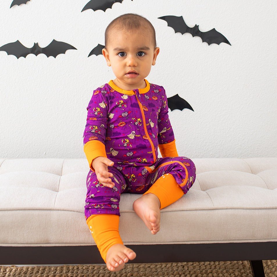 Purple baby coverall with flower and bat prints, long sleeves, footed design, and a full-length front zipper.