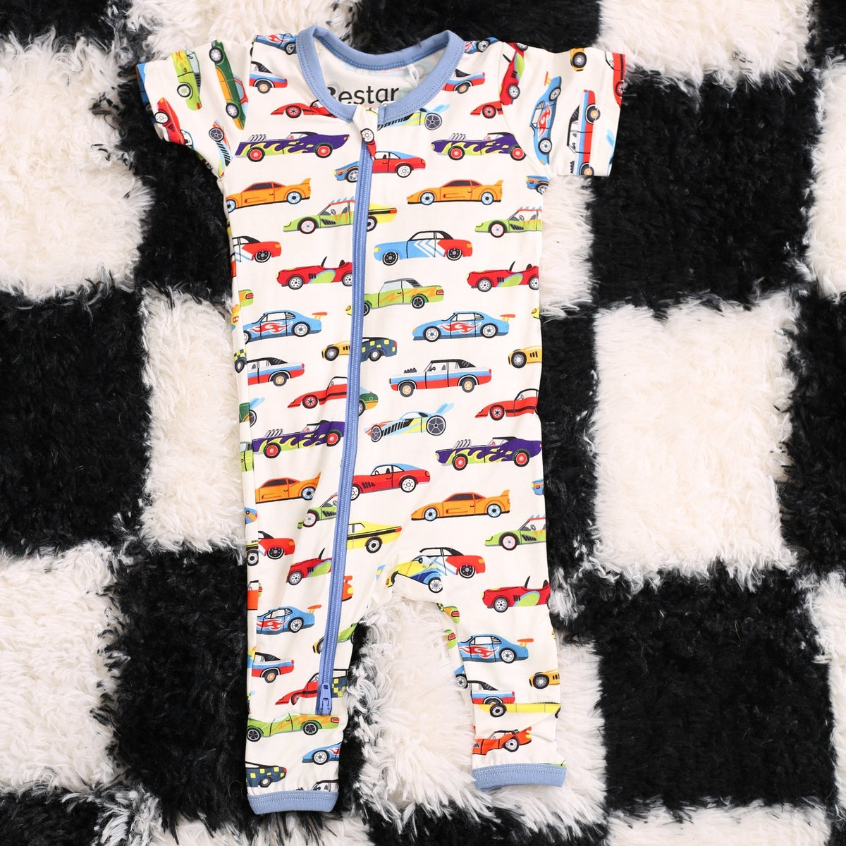 Baby coverall with a whimsical racing cars print, long sleeves, fold-over feet, and a full-length front zipper