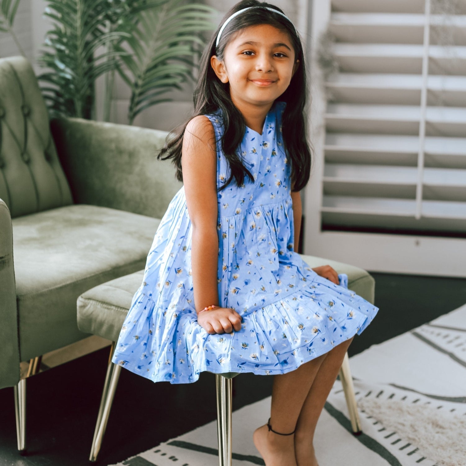 Blue baby dress with a pattern of small muted yellow and blue flowers all over.