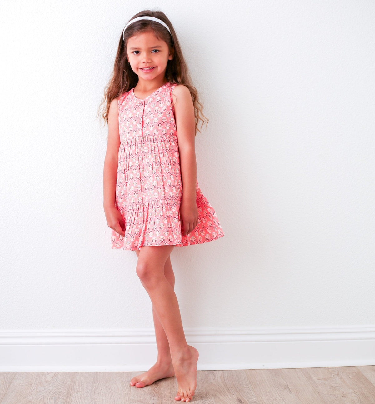 Hot pink baby dress with yellow and pink floral print, ruffle detail, and back-button pull-on style.